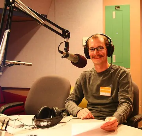 Persoon achter een microfoon in een audiostudio